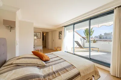 a bedroom with a bed and a large window at REF 823 - Cannes Center - Duplex apartment for rent in Cannes