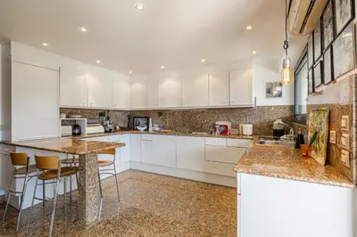 a kitchen with white cabinets and a island with bar stools at REF 823 - Cannes Center - Duplex apartment for rent in Cannes