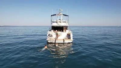 a man in the water in front of a boat at Superbe yacht dans le port de Cannes in Cannes
