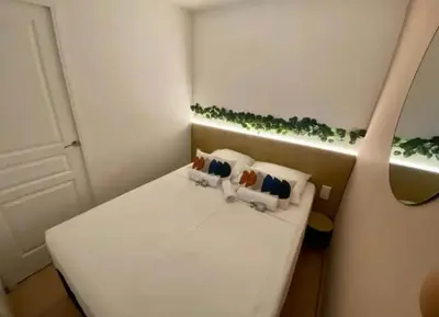 a small room with a white bed with pillows at T2 Vue Mer à Cannes in Cannes