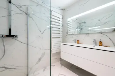 a white bathroom with a glass shower and a sink at Spacious 2-Br Apartment in a Residence with Pool in Cannes