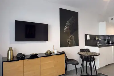a living room with a table and a tv on the wall at BEAUTIFUL 1 - BR APARTMENT - Next To Rue Antibes in Cannes