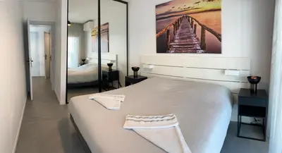 a bedroom with a white bed with a painting on the wall at BEAUTIFUL 1 - BR APARTMENT - Next To Rue Antibes in Cannes