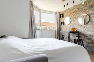 a bedroom with a white bed and a brick wall at Joséphines in Cannes