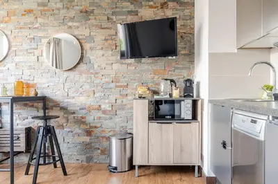 a kitchen with a tv on a brick wall at Joséphines in Cannes