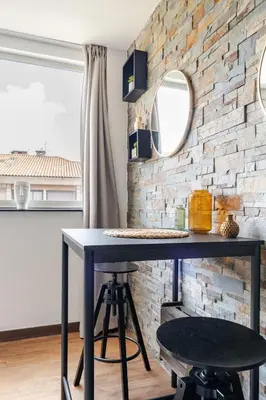 a table with two stools in front of a brick wall at Joséphines in Cannes