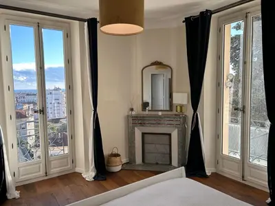 a bedroom with a fireplace and large windows at Spacieux proche Palais Festival in Cannes
