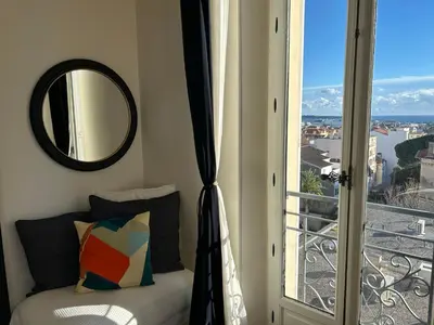 a bedroom with a mirror and a window with a view at Spacieux proche Palais Festival in Cannes