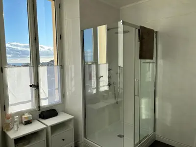 a white bathroom with a shower and a window at Spacieux proche Palais Festival in Cannes