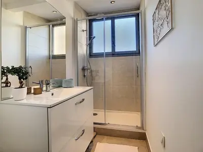 a white bathroom with a shower and a sink at Beautiful modern apartment in Cannes in Cannes