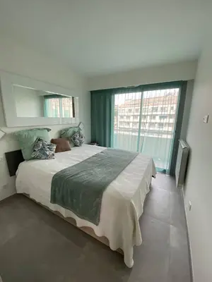 a bedroom with a large bed and a large window at Cannes centre-ville - Face mer 3 pièces avec terrasse in Cannes