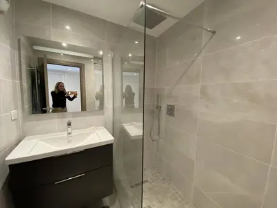 a woman taking a picture of a bathroom with a sink and shower at Cannes centre-ville - Face mer 3 pièces avec terrasse in Cannes