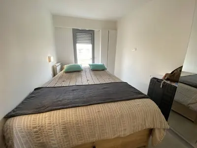 a bedroom with a large bed with two green pillows at Cannes centre-ville - Face mer 3 pièces avec terrasse in Cannes