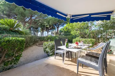 a table and chairs under an umbrella on a patio at Garden level Croisette sea view with garage in Cannes