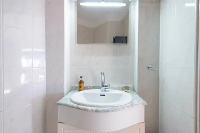 a white bathroom with a sink and a mirror at Garden level Croisette sea view with garage in Cannes