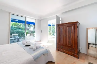 a bedroom with a large bed and a large window at Garden level Croisette sea view with garage in Cannes