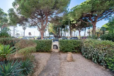 a garden with a statue and trees and a parking lot at Garden level Croisette sea view with garage in Cannes