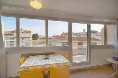 a dining room with a table and chairs and windows at Edouard - Piscine-Parking - VCA in Cannes