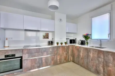 a kitchen with white appliances and wooden cabinets at superbe 3 chambres proche palais et croisette dag13 in Cannes