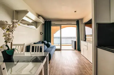 a living room with a blue couch and a kitchen at Le Cannes Beach 799 - terrasse vue mer panoramique in Cannes