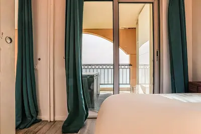 a bedroom with green curtains and a view of a balcony at Le Cannes Beach 799 - terrasse vue mer panoramique in Cannes