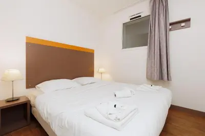 a bedroom with a large white bed with white towels on it at RIO - 200 m plages - App 6pers- climatisé, terrasse, piscine, parking in Cannes