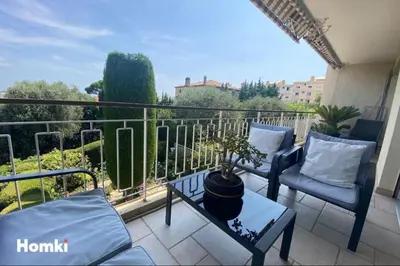 a balcony with two chairs and a potted plant on it at Le Royal in Cannes