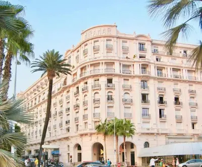 a large building with palm trees in front of it at MIRAMAR-Studio tout confort sur la croisette in Cannes