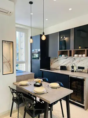 a dining room with a table and chairs and a kitchen at 3 pièces en cœur de cannes in Cannes