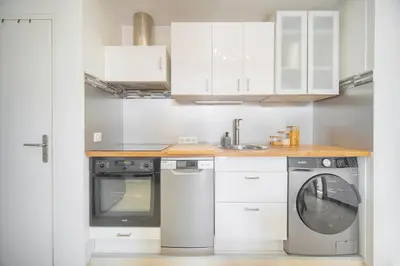 a kitchen with white cabinets and a washing machine at Charmant duplex proche de Cannes centre et à 2min à pied de la mer in Cannes