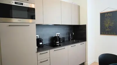 a kitchen with white cabinets and a black wall at Proche Carlton & Croisette, Appartement 202 - Palmazur Vacances in Cannes