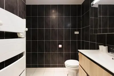 a black tiled bathroom with a toilet and a sink at L'Azuréa - Centre - Plage - Wifi - Climatisation in Cannes