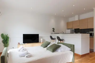 a bedroom with a white bed and a kitchen at L'Azuréa - Centre - Plage - Wifi - Climatisation in Cannes