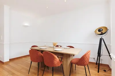 a dining room table with orange chairs and a spotlight at L'Azuréa - Centre - Plage - Wifi - Climatisation in Cannes
