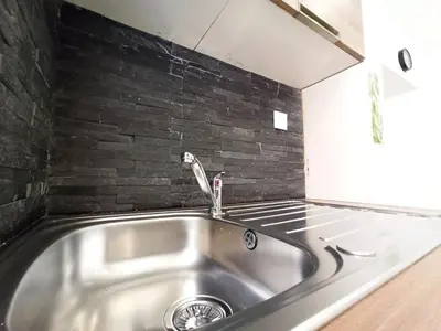 a stainless steel sink in a kitchen with a brick wall at Viva Riviera 6 Rue Commandant André in Cannes