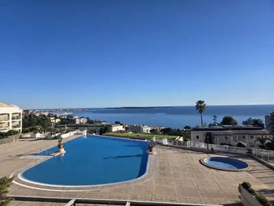 a blue swimming pool with the ocean in the background at Sisley 1061 - F2 Terrasse avec vue mer in Cannes