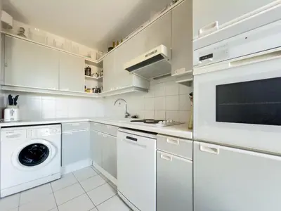 a kitchen with white cabinets and a washer and dryer at The Artist by Winsome Destination in Cannes