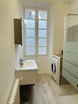 a white bathroom with a sink and a window at Appartement Roi Albert in Cannes