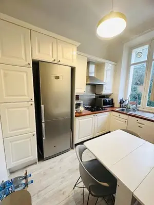 a kitchen with a white table and a refrigerator at Appartement Roi Albert in Cannes