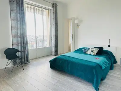 a bedroom with a blue bed and a window at Appartement Roi Albert in Cannes