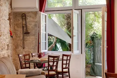 a dining room with a table and chairs and a window at À 1km Plage du Midi et Palais des Festivals - Appartement Centre Cannes avec Cour Extérieur Privée in Cannes