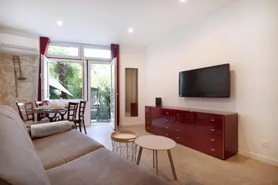 a living room with a couch and a tv on a wall at À 1km Plage du Midi et Palais des Festivals - Appartement Centre Cannes avec Cour Extérieur Privée in Cannes