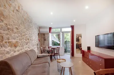 a living room with a couch and a stone wall at À 1km Plage du Midi et Palais des Festivals - Appartement Centre Cannes avec Cour Extérieur Privée in Cannes