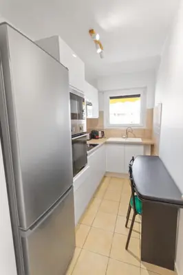 a kitchen with a stainless steel refrigerator and a table at Le Chambord - Hypercentre - Spacious - Terrace in Le Cannet