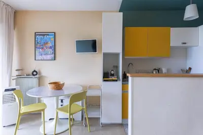 a kitchen with a table and yellow chairs in a kitchen at Terrasse de Timily - Vue mer, plage, clim, parking in Cannes
