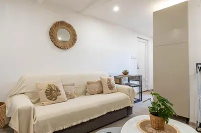 a white living room with a couch and a mirror at L’Espérance dAzur - 500 m de la plage in Cannes