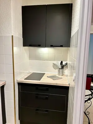 a kitchen with black cabinets and a counter top at Cosy studio near La Croisette and the beach in Cannes