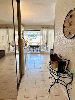 a living room with a table and a clock on the wall at Cosy studio near La Croisette and the beach in Cannes