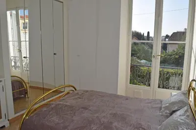 a bedroom with a bed and a large window at Winter Palace in Cannes