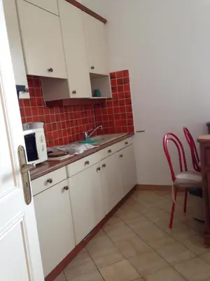 a kitchen with white cabinets and a red tile wall at Winter Palace in Cannes